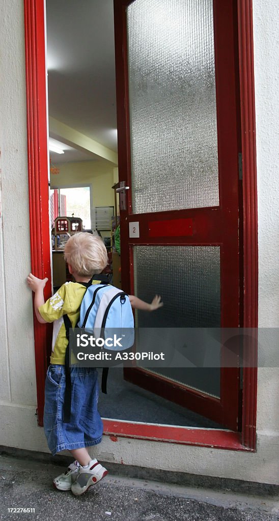A boy waiting at a door for the first day of kindergarten Little boys very first day of school. Door Stock Photo