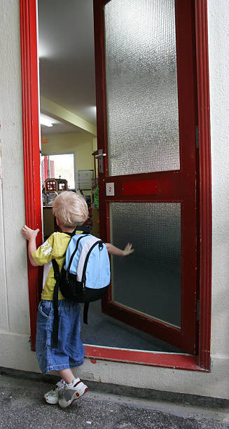 A boy waiting at a door for the first day of kindergarten stock photo