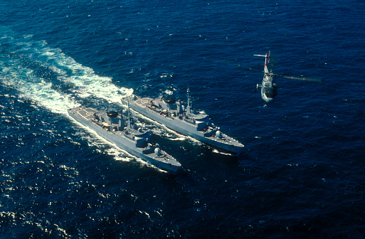 An helicopter over two warships in a war operation.I used a slide film.