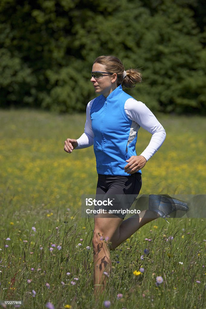 young woman running 5 young woman running over meadow with flowers Active Lifestyle Stock Photo