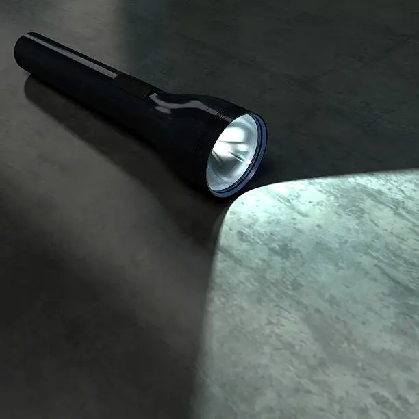 Photo of Black flashlight illuminating part of a dark metallic floor