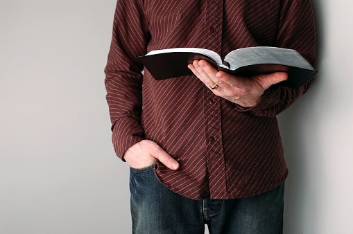 Casually-dressed Christian guy holding his open Bible.