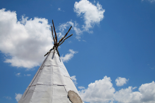 Image of a teepee with cloud background.