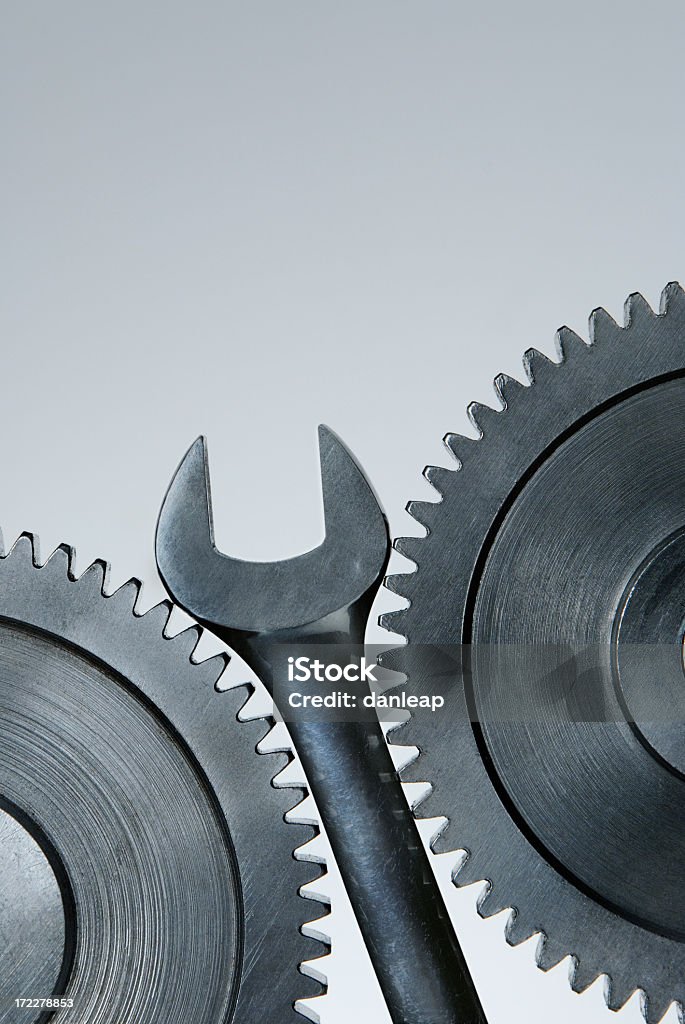 Wrench in the Works Steel spanner stuck between two steel cogs Throwing Stock Photo
