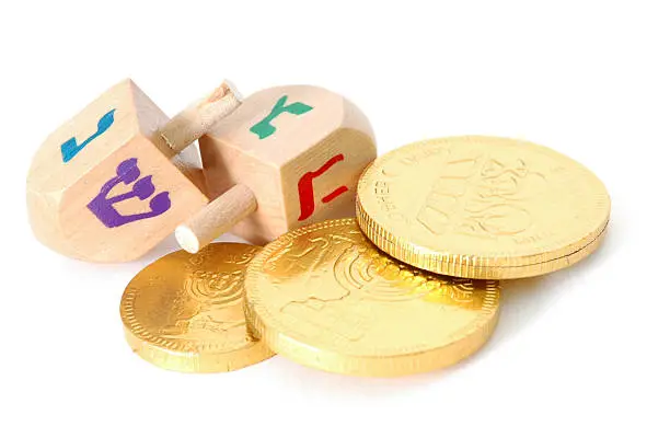 Two dreidels and a small pile of gelt (traditional Hanukkah chocolate coins) isolated on white.Also available: