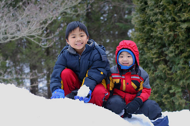 Two young boys having fun playing in the snow and looking very happy.