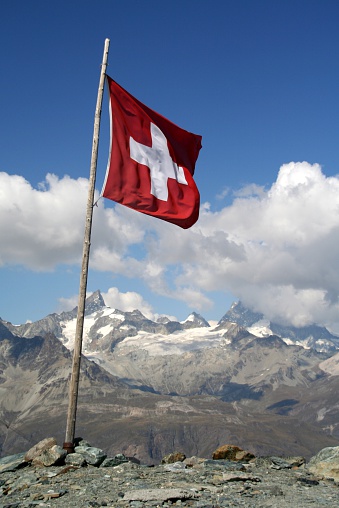 Switzerland flag with nice mountains behind.