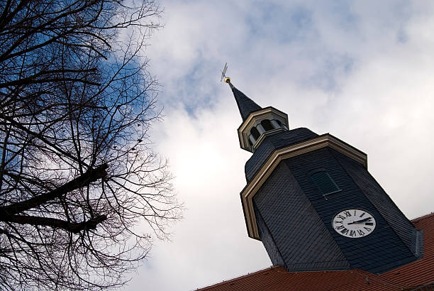 Church tower with clock in a small village with blue sky