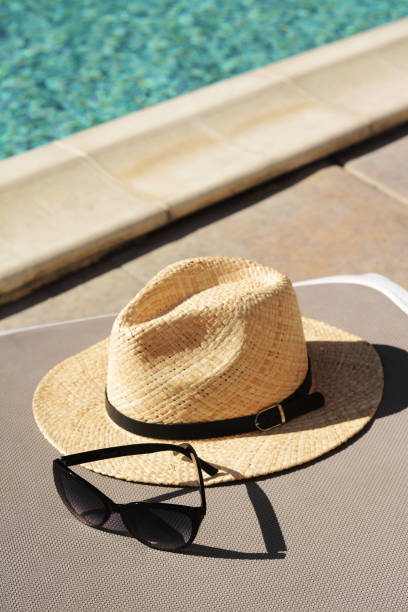 istock Stylish straw hat and sunglasses on grey sunbed at poolside. Beach accessories 1722808069