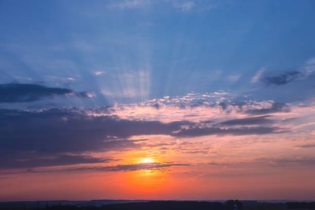 Sunrise with sun rays sunlight  in  clouds against bright blue sky