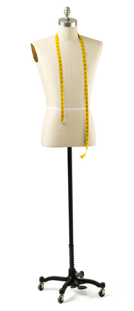Tailor's male mannequin torso with measuring tape around shoulders on stand.	