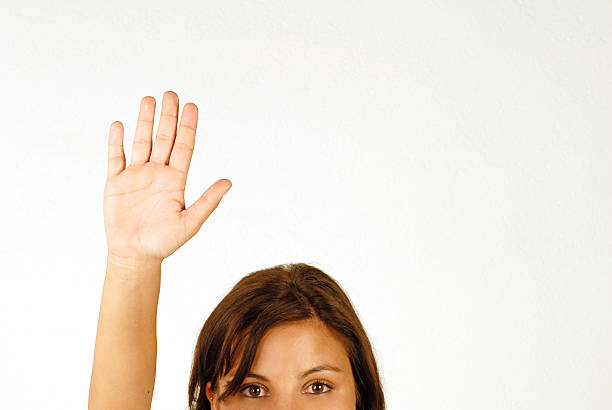Woman with bright eyes and hand up over a white background stock photo