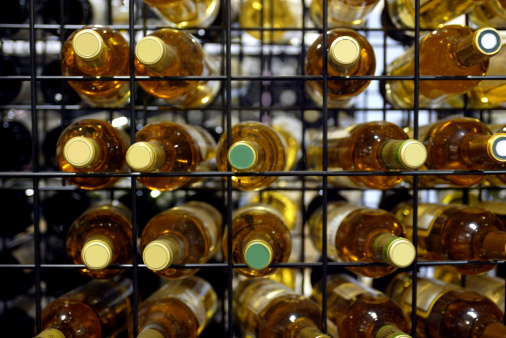 Wine bottles in a rack with corks facing the camera.