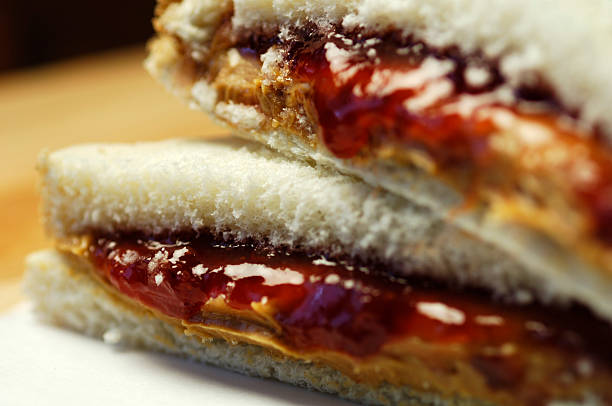 Close up of peanut butter and jelly sandwich on white bread stock photo