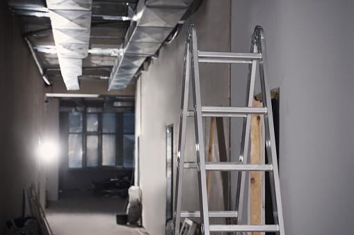 Metal ladder and building materials in hall prepared for renovation