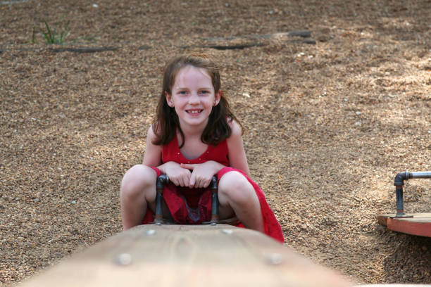 Happy eight year old girl on the end of a see saw or teeter totter