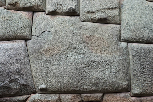 A carved, complex wall stone with twelve corner points on a street in Cuzco, Peru. Inca natives sculpted the intricate angles to fit precisely into other rocks on the natural material surface. The built structures are architectural marvels and archeological mysteries of technique. Horizontal format with copy space and no people. 
