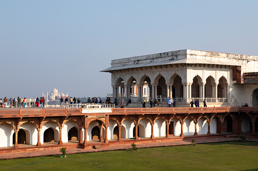 3rd February, 2020 - Agra, India: The Red Fort, a UNESCO World Heritage site, stands as an enduring symbol of India's rich history and Mughal architectural prowess. Both tourists and local visitors are seen exploring the massive fort complex. Built primarily of red sandstone, the fort once served as the main residence of the Mughal emperors. Notably, from various points within the fort, one can catch distant views of another iconic landmark, the Taj Mahal. The people in the photographs are engaged in various activities, from taking selfies to enjoying the panoramic views, making this a bustling hub of cultural interaction and historical exploration.