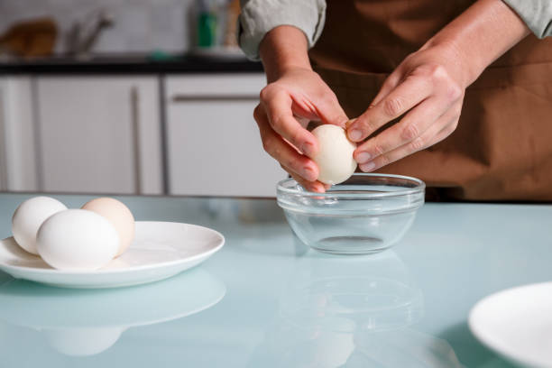 istock Female hands peeling off boiled egg shell on a kithcen table over glass plate. 1722828442