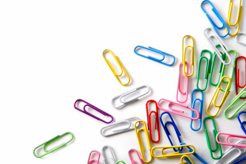 Close-up of multi-colored paper clips on a white background.