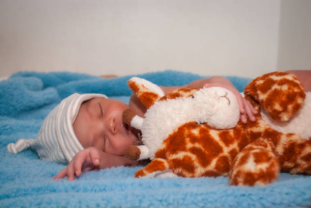 Beautiful baby asleep in his bed with blue sheets and white balls like a little angel