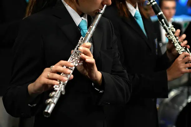 Flutists. Focus on the visible part of the face of first player. Blured drum in the background.Similar photos: