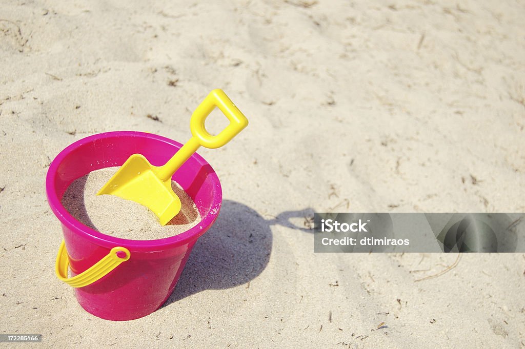 Pink bucket and yellow shovel in the sand Sand filled pink bucket and yellow shovel in the sand. Lots of copy space.Here are some related images: Sand Pail and Shovel Stock Photo
