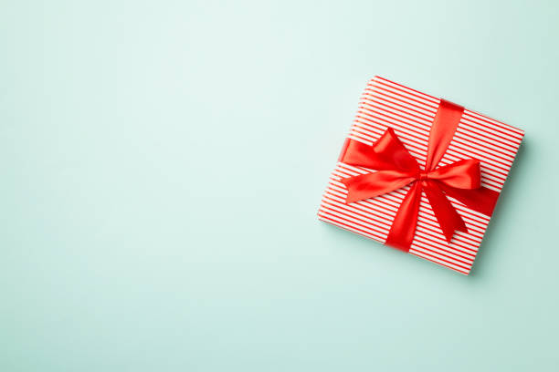 istock Gift box with red ribbon bow on color background, top view 1722858982