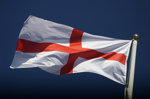 England flag of St George waving outdoors in the wind against a bright blue sky