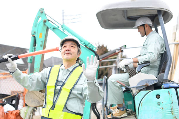 istock A man operating construction machinery at a construction site and a middle-aged Asian male worker using a guide rod to direct traffic 1722869283