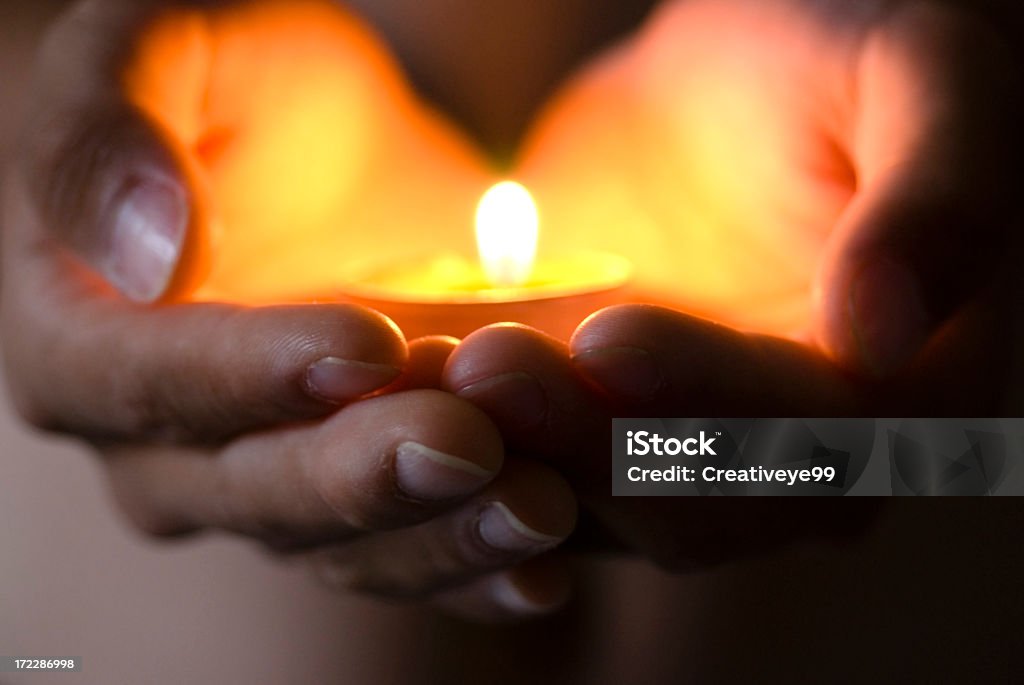 Hope illuminates Hand holding candle light. Symbol of hope, peace and love. Candle Stock Photo