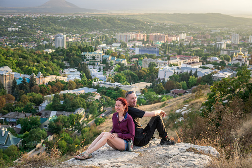Young couple sitting at the top of a hill, smiling