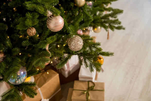 istock Big beautiful christmas tree decorated with beautiful shiny baubles and many different presents on wooden floor. White wall background with copy space. 1722877055