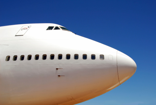 The nose and front windows of a large white jet shot from a low angle against a clear blue sky.New to iStockphoto Click the badge below to sign up now: