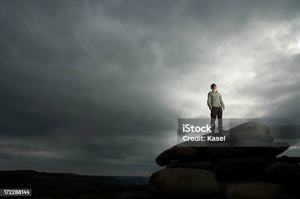 Photo libre de droit de Un Homme Sur Un Rocher En Face De Ciel Menaçant banque d'images et plus d'images libres de droit de Marcher - Marcher, Musique rock, Adulte