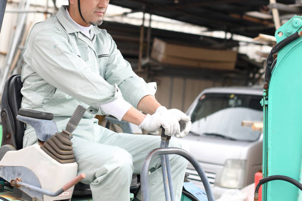 Middle-aged Asian male worker operating construction machinery at a construction site