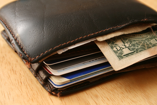 Closeup view of wallet with one old dollar bill in it and some credit cards