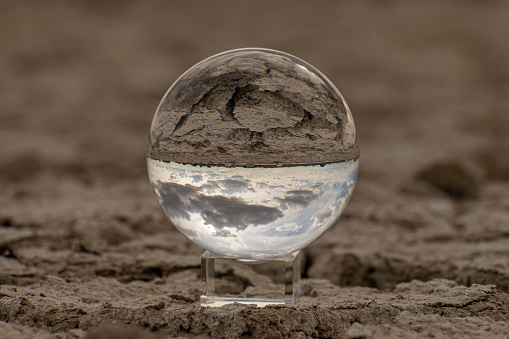 In the photograph you can see a transparent glass ball, in which you can see the dry and cracked earth of a lake produced by the drought.