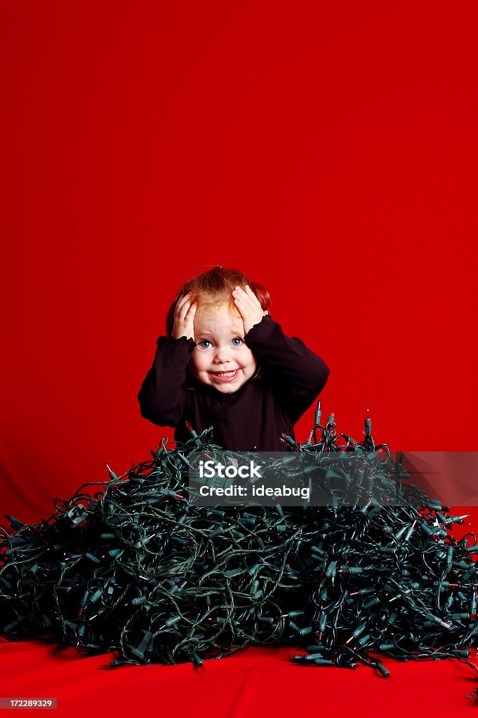 Niño abrumado por pila de luces de Navidad desmelenado - Foto de stock de Navidad libre de derechos