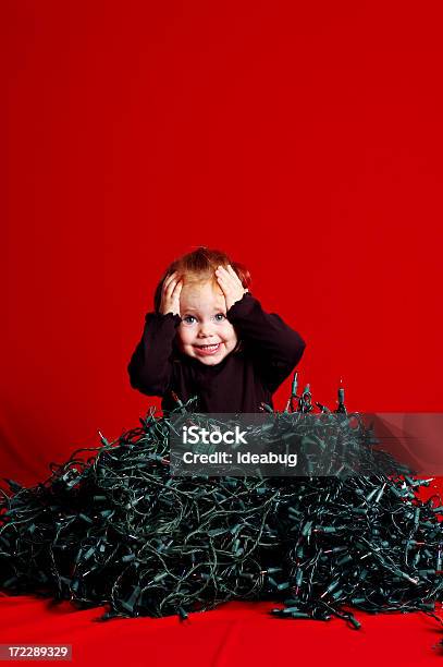 Niño Abrumado Por Pila De Luces De Navidad Desmelenado Foto de stock y más banco de imágenes de Navidad
