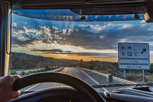 View from the driving position of a truck of a highway with a 24-hour service area informative traffic sign.