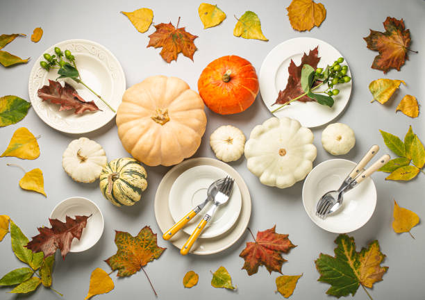 istock Thanksgiving festive table composition with different colourful pumpkins, autumn leaves, empty plates with cutlery on light grey background table ready for party and celebration 1722895633