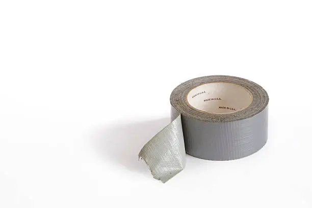 Roll of gray adhesive duct tape on white background. 