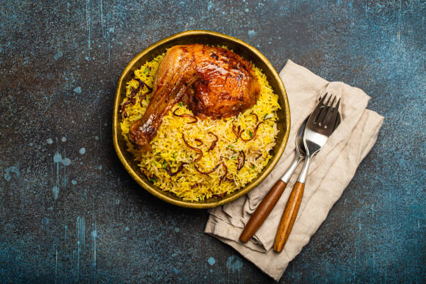 Indian dish Biryani chicken with basmati rice in metal brass old bowl on table