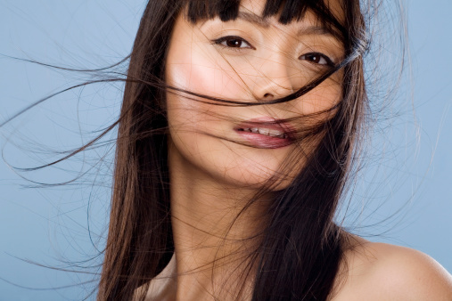 Asian woman with hair flying on wind.