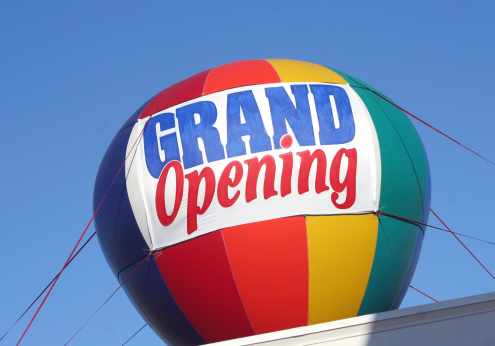 a colorful balloon on top of a building announcing a grand opening of the business