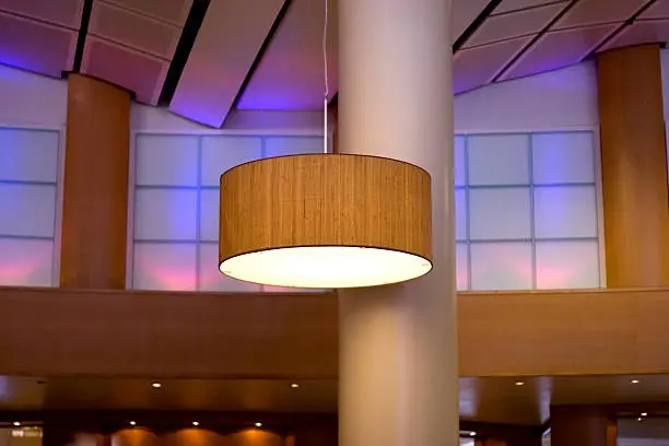 Detail shot from modern hotel lobby. A big lamp hanging from the roof. Ambient light in the background.