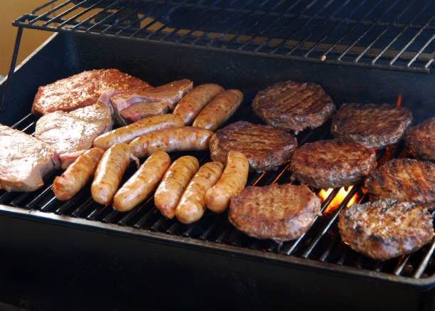Meat on the BBQ "Steaks, sausage and burgers on a BBQ. See also" bbq smoker stock pictures, royalty-free photos & images