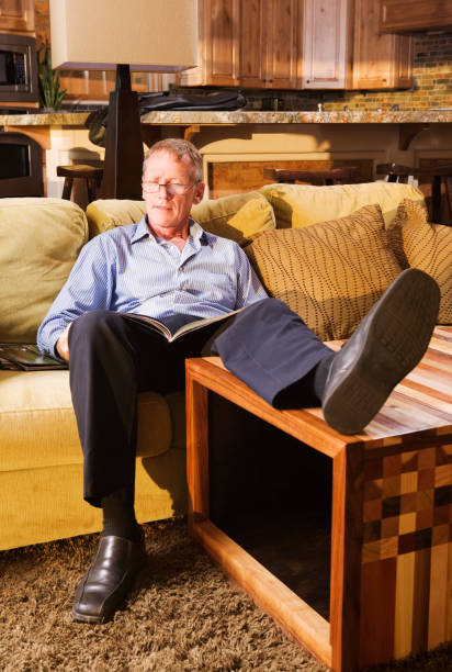 istock Senior man relaxing on couch and reading a magazine 172292810