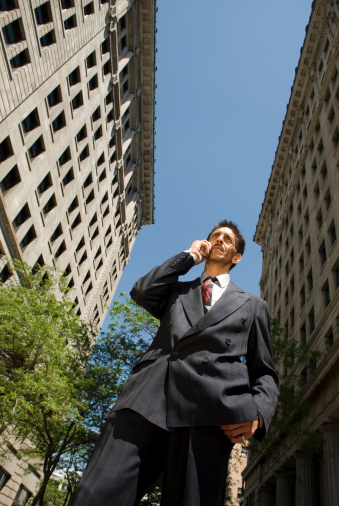 A business man on a phone standing in a city.